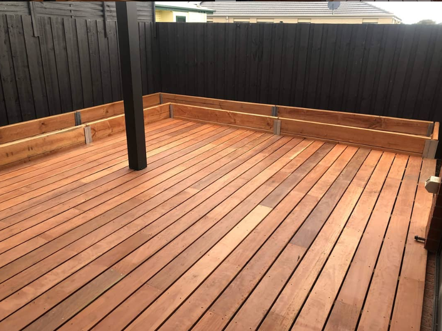 A newly constructed timber deck with planter boxes surrounding the deck within a fenced area